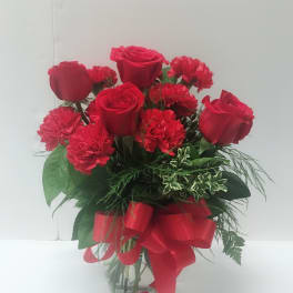Red roses and carnations in a glass vase with a red ribbon