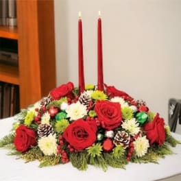Low floral centerpiece with red roses and two red taper candles