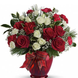 Red and white roses arranged in a red vase with a plaid ribbon
