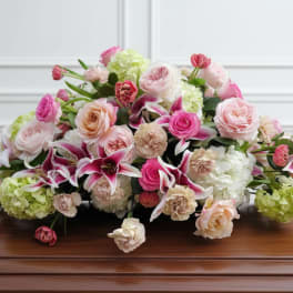 Low floral arrangement of pink and white roses with lilies and green hydrangeas