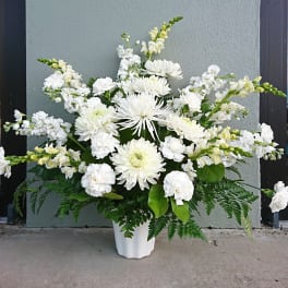 White floral arrangement in a white vase with mixed blooms and greenery
