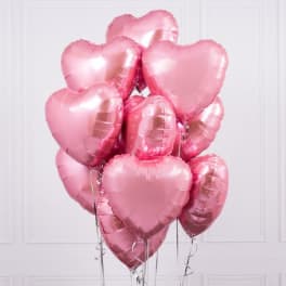 Cluster of shiny pink heart-shaped foil balloons with silver ribbons