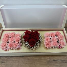 Open gift box with pink carnations and red roses arranged in three sections