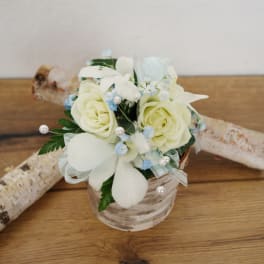 Small bouquet of white roses and pale blue accents in a glass vase