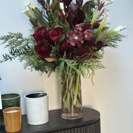 Deep burgundy bouquet with white calla lilies in a clear glass vase