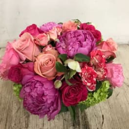 Bouquet of pink and purple roses with peonies on a wooden surface