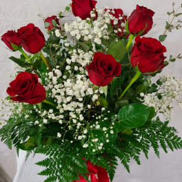 Red roses with white baby's breath in a bouquet with fern foliage