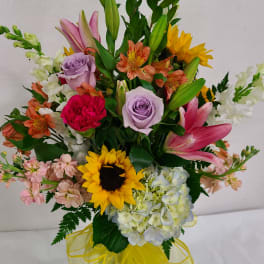 Mixed bouquet with sunflowers, lilies, roses, and hydrangeas in a glass vase