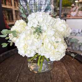 White hydrangea bouquet in a clear glass vase with eucalyptus