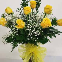 Yellow roses with baby's breath in a glass vase tied with a yellow ribbon