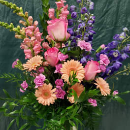 Tall mixed bouquet in a glass vase with pink roses and peach daisies