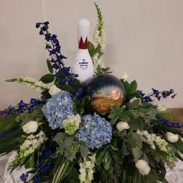 Floral arrangement with blue and white flowers around a bowling pin and ball