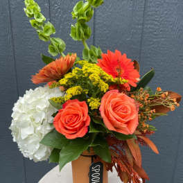 Orange and white floral arrangement in a vase with tall green spikes