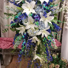 Tall floral spray with white lilies and blue flowers on a stand