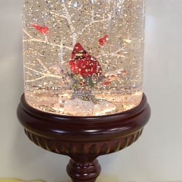 Snow globe with a red cardinal on a wooden pedestal