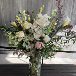 Tall floral arrangement in a glass vase with white orchids and roses