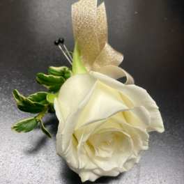 White rose boutonniere with green leaves and a gold ribbon