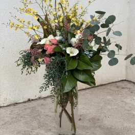 Tall mixed bouquet in a clear glass vase with pink, white, and yellow flowers