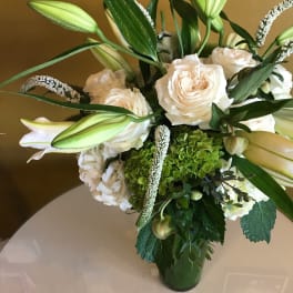 White roses and lilies arranged in a glass vase