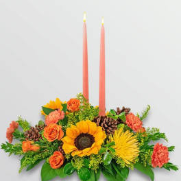 Floral centerpiece with two pink taper candles and autumn-colored blooms