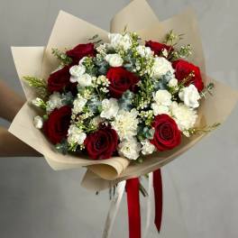 Bouquet of red roses and white carnations wrapped in beige paper