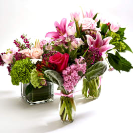 Three colorful flower arrangements in glass vases on a white background