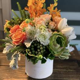 Orange and white floral arrangement in a white vase