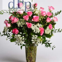 Pink roses and white filler flowers in a clear glass vase