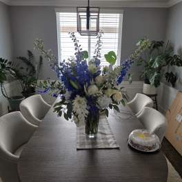 Blue and white floral arrangement in a clear glass vase on a dining table