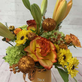 Halloween bouquet with orange roses, yellow daisies, lilies, and glitter pumpkins in a Trick or Treat vase