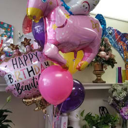 Unicorn-shaped birthday balloons with a pink birthday balloon and a pink helium balloon