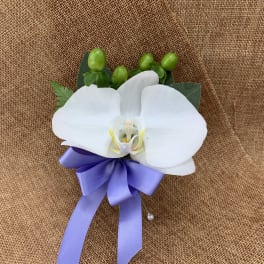 White orchid corsage with a purple ribbon on burlap