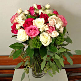 Bouquet of pink, red, and white roses in a clear glass vase