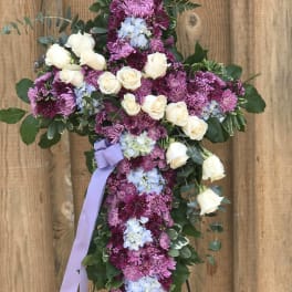 Cross-shaped floral tribute with white roses and purple blooms