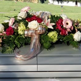 Casket spray with roses, lilies, gerbera daisies, and ribbon