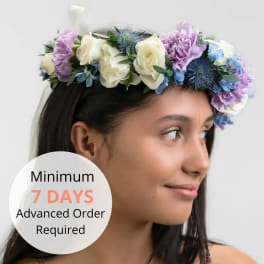 Floral crown of white roses, lavender blooms, and blue accent flowers worn on a woman's head