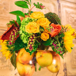 Yellow and orange roses in a glass bowl with apples