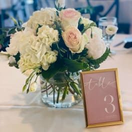 White and blush floral centerpiece in a glass vase on a table