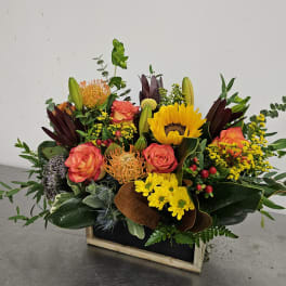 Mixed bouquet with sunflowers, coral roses, and yellow mums in a wooden box