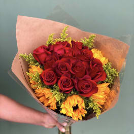 Bouquet of red roses and yellow-orange flowers wrapped in brown paper