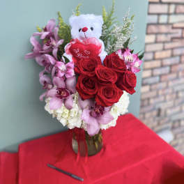 Bouquet of red roses and pink orchids with a teddy bear topper