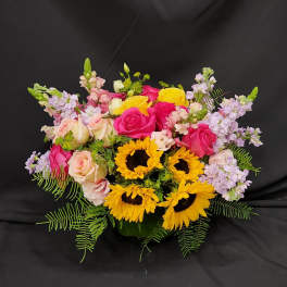 Mixed bouquet with roses, sunflowers, and lavender blooms in a vase