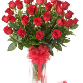 Bouquet of red roses in a clear glass vase with a red ribbon