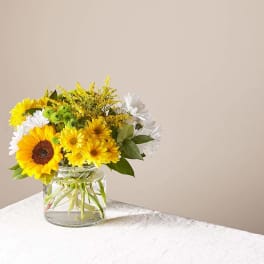 Yellow and white flowers in a clear glass vase