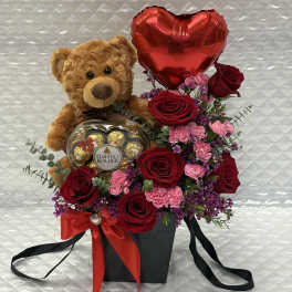 Teddy bear with roses, a heart balloon, and chocolates in a gift box