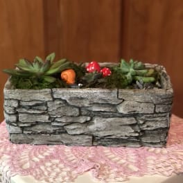 Succulent arrangement in a stone-look rectangular planter with small decorative mushrooms