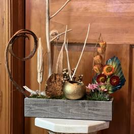 Decorative floral arrangement in a gray wooden box with dried accents and colorful blooms