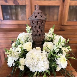 White floral arrangement around a decorative lantern centerpiece