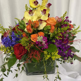 Colorful mixed flower arrangement in a square glass vase