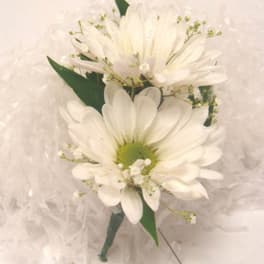 White daisy boutonniere with small white filler flowers and pearl pin on a soft white background